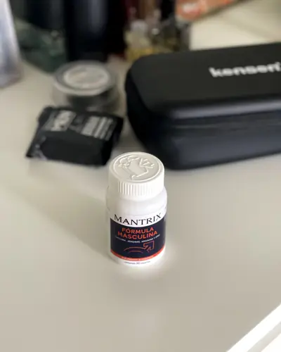 Frasco blanco junto a un neceser negro en la barra del baño